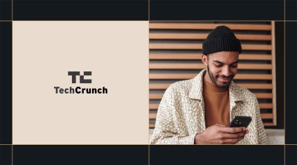 TechCrunch logo next to a man in a beanie smiling while looking at his phone.