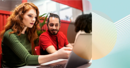 Two coworkers examining a laptop screen together.