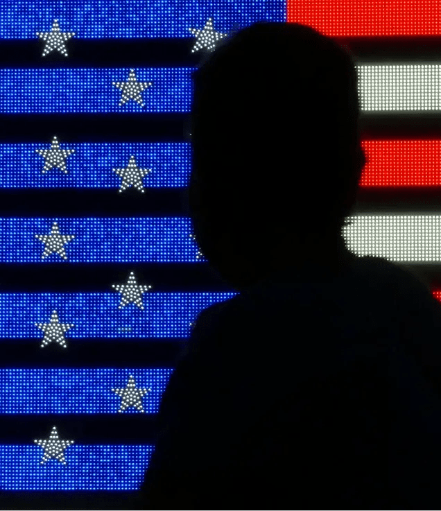Silhouette of a person in front of a digital display of the United States flag.