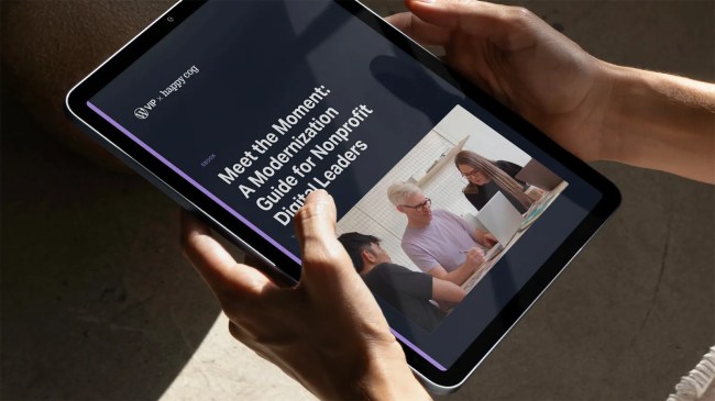 Person holding a tablet displaying a nonprofit digital transformation guide with a photo of three people working together.