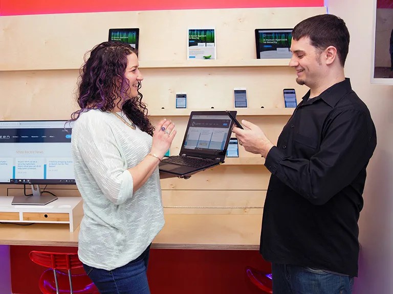 Two people smiling together while using a laptop and phone for digital solution content collaboration.