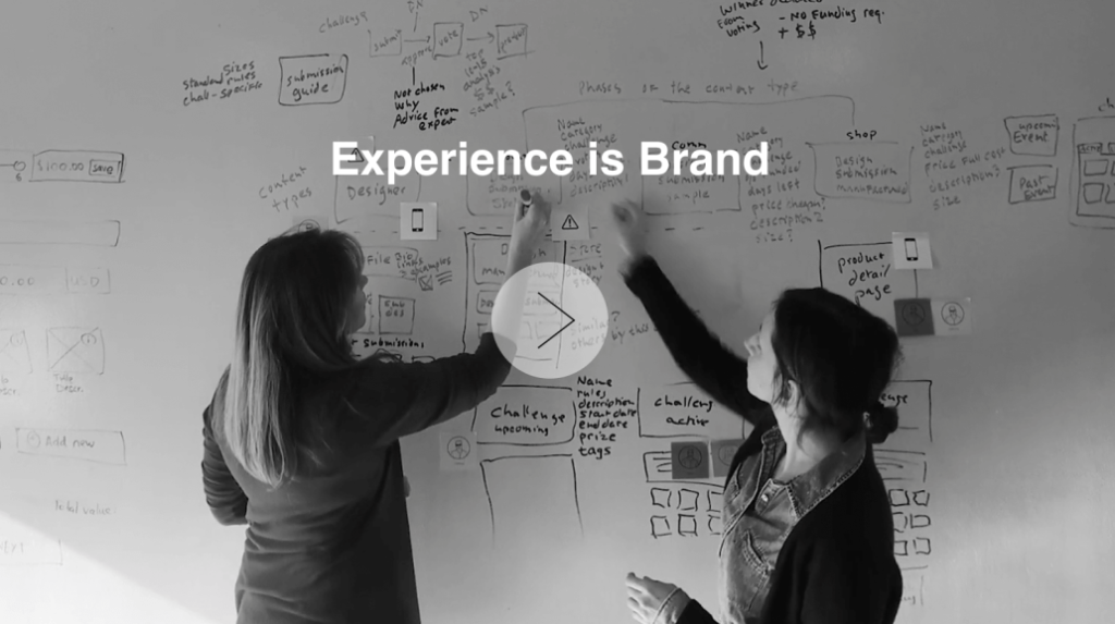Two people brainstorming digital solution content strategy with Experience is Brand text central overlay.