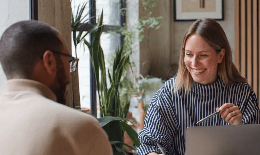 Two colleagues discussing ideas over a laptop during a planning meeting using a CMS for marketers.