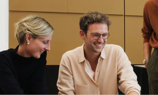 Coworkers looking at shared work and smiling during a team session.