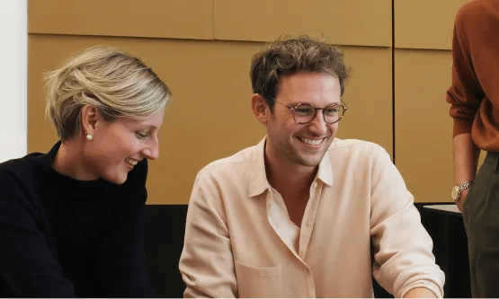 Coworkers looking at shared work and smiling during a team session.