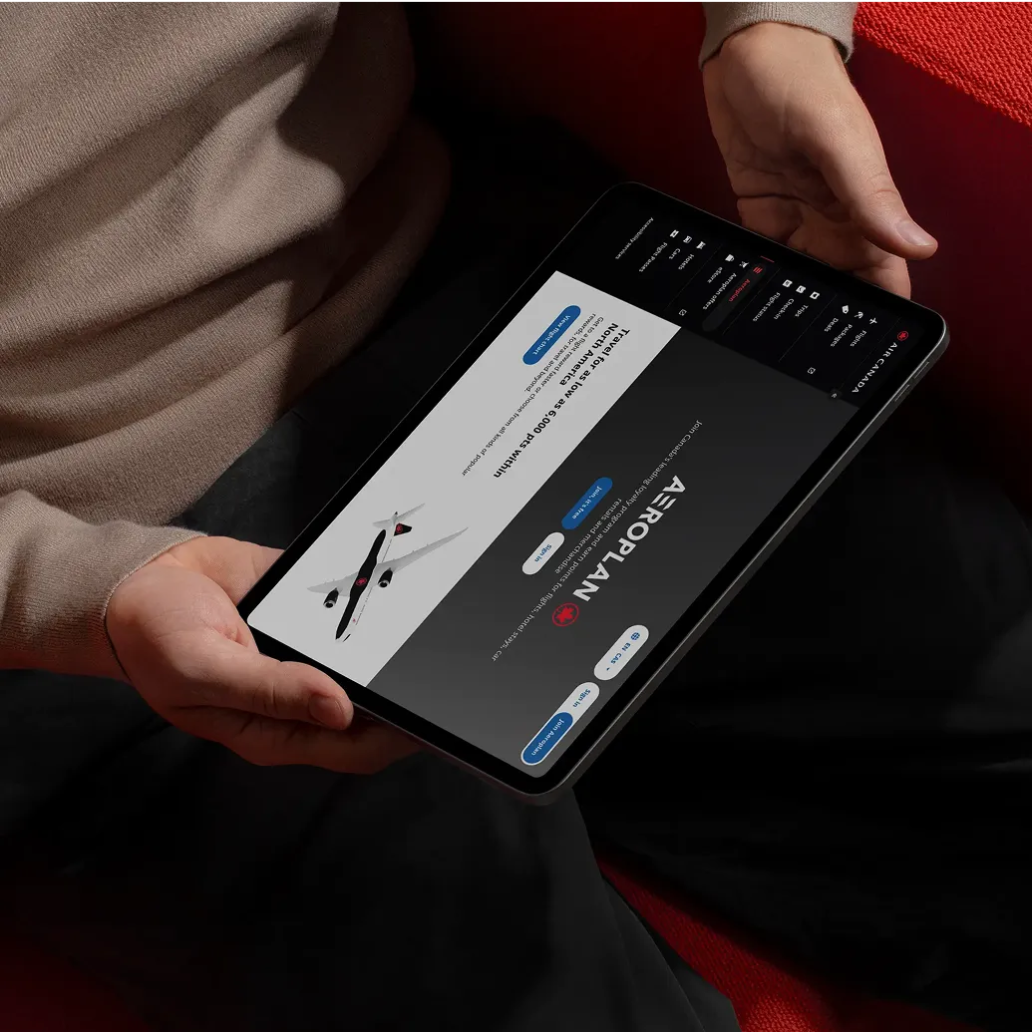 Person holding a tablet displaying the Aeroplan website with a flight booking screen and airplane graphic.
