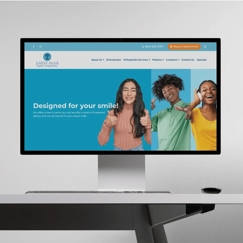 Desktop monitor displaying the Ashby Park Family Orthodontics website featuring smiling teens and the headline “Designed for your smile!”.