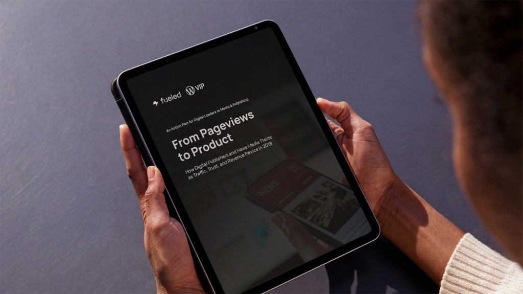 Close-up of a person holding a tablet displaying a whitepaper cover titled “From Pageviews to Product” by Fueled and WordPress VIP, illustrating digital publishing trends and how leading publishers are adapting monetization models, workflows, and platforms in a changing media landscape.